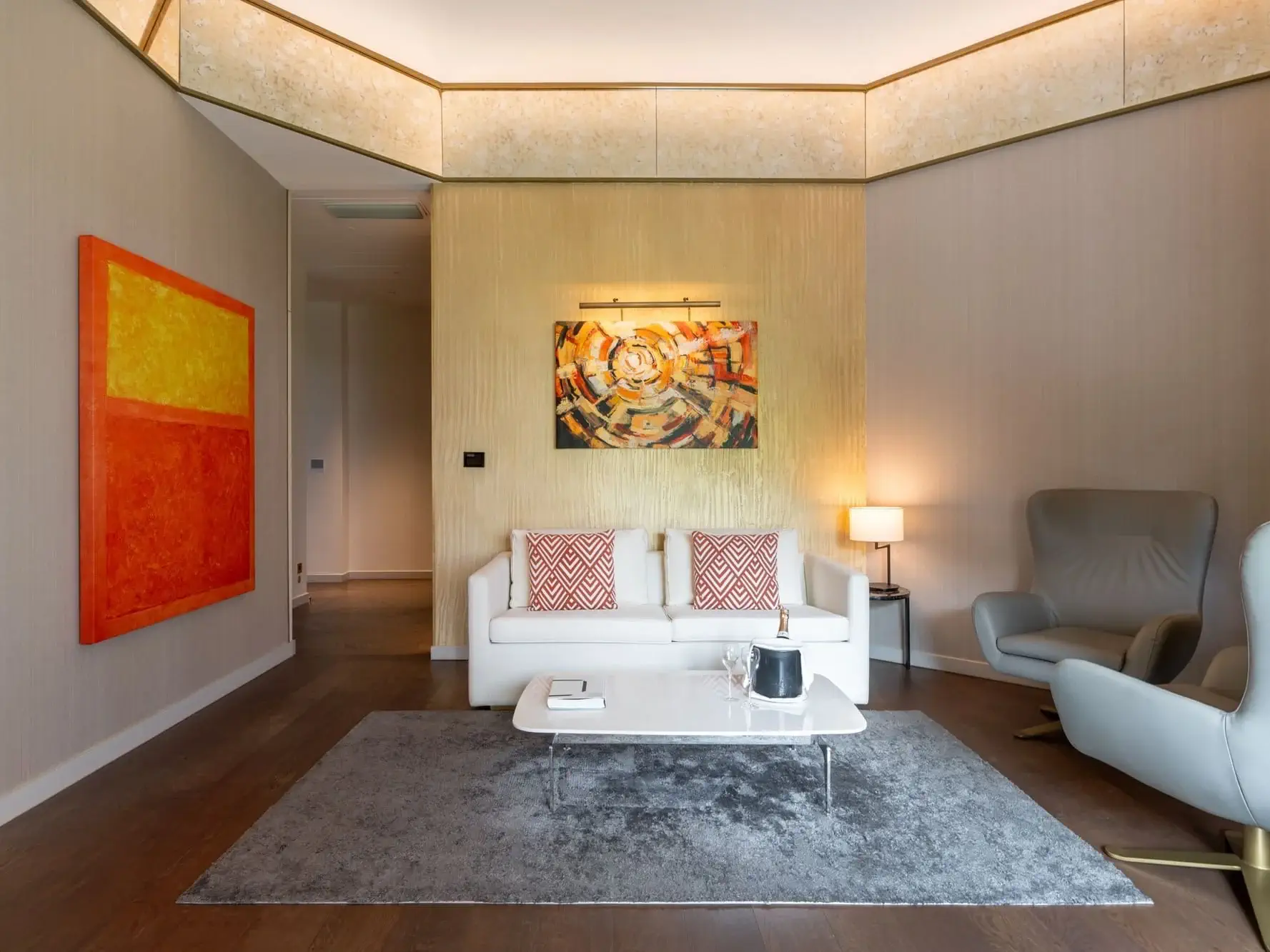 Modernes Wohnzimmer in der Almanac Family Suite mit einem weißen Sofa, gemusterten Kissen, abstrakten Gemälden, einem grauen Sessel, einem Couchtisch und einem grauen Teppich auf Holzboden.