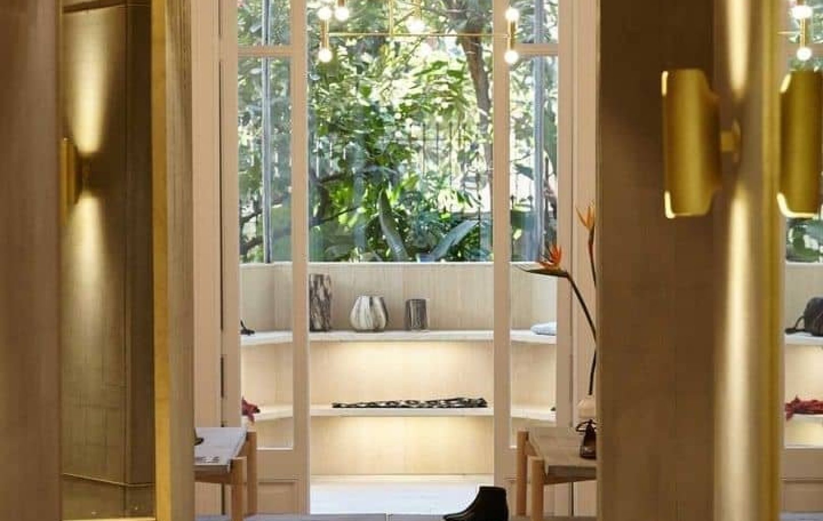 Un interior de boutique moderna amb prestatges que mostren sabates i accessoris a prop de grans finestrals amb vistes a la vegetació.