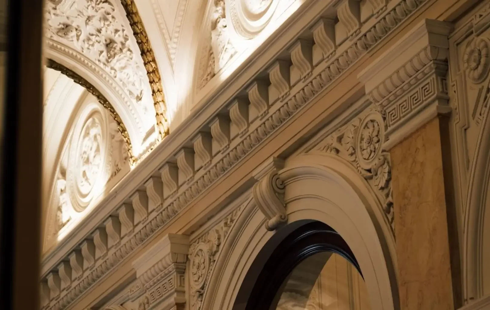 Detaillierte architektonische Stuckarbeiten und kunstvolle Schnitzereien schmücken ein gewölbtes Portal und die Decke mit klassischen Mustern und komplizierten Reliefs, die die Suite zu einem Erlebnis in diesem hellen Raum machen.
